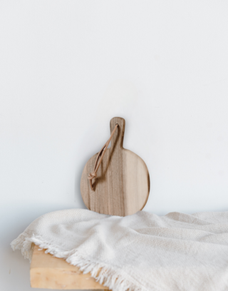 Notre planche ronde posée contre un mur sur une table en bois avec un plaid écru