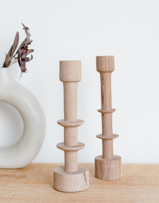 Notre chandelier en noyer posé sur une table en bois près d'un vase arrondis blanc