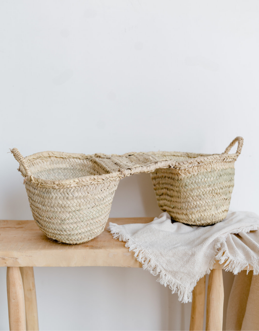 Notre panier double style dos d'âne posé sur une table en bois et sous un plaid écru