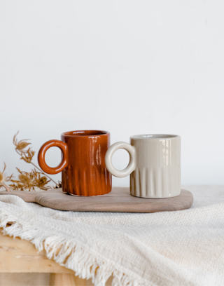 Notre collection de tasse creusée avec sa anse ronde posées sur une planche en bois près d'un plaid écru et d'une fleur séchée