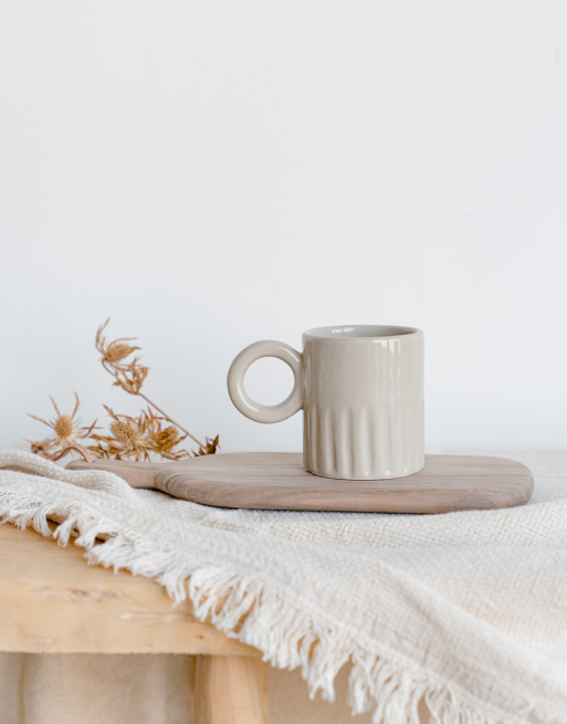 Notre tasse creusée beige posée sur une planche en noyer