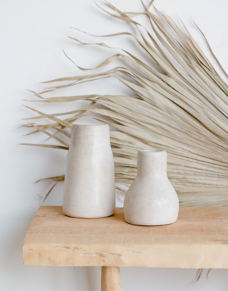 Notre duo de vase marocain en Tadelakt posés sur une table en bois près d'un feuille de palmier séchée