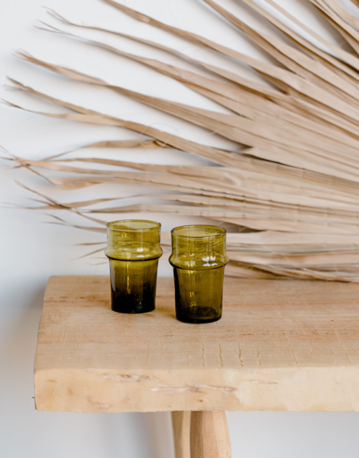 Notre duo de verre à thé ambre posés sur une table en bois près d'une feuille de palmier