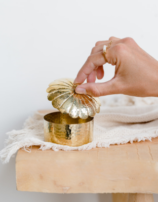 Notre jolie boîte à bijoux en forme de fleur en laiton dorée posée sur une table en bois